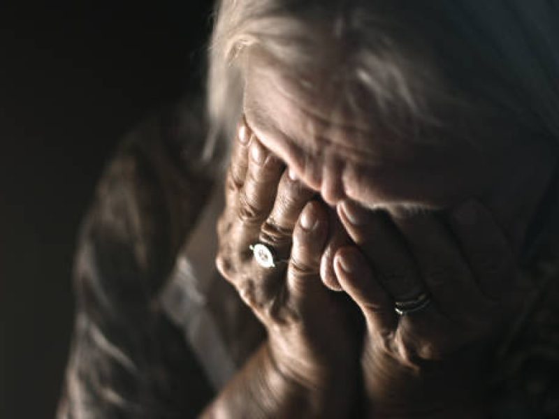 Desperate senior crying in a dark room. Perfectly usable for a wide range of topics like depression, loneliness or mental health in general.